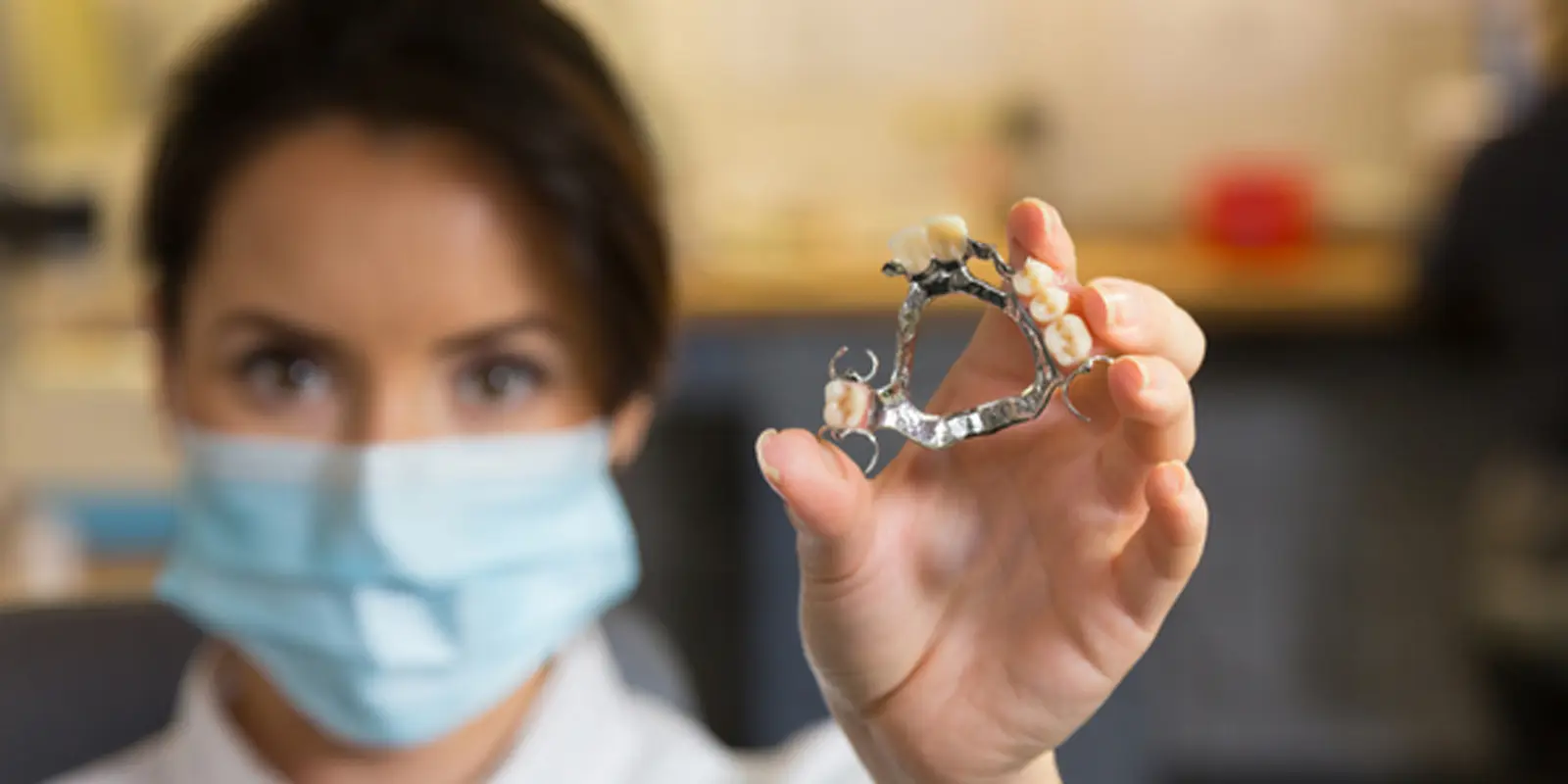 Dental technician holding a chrome partial denture framework at Chrome Cast Dental Laboratory